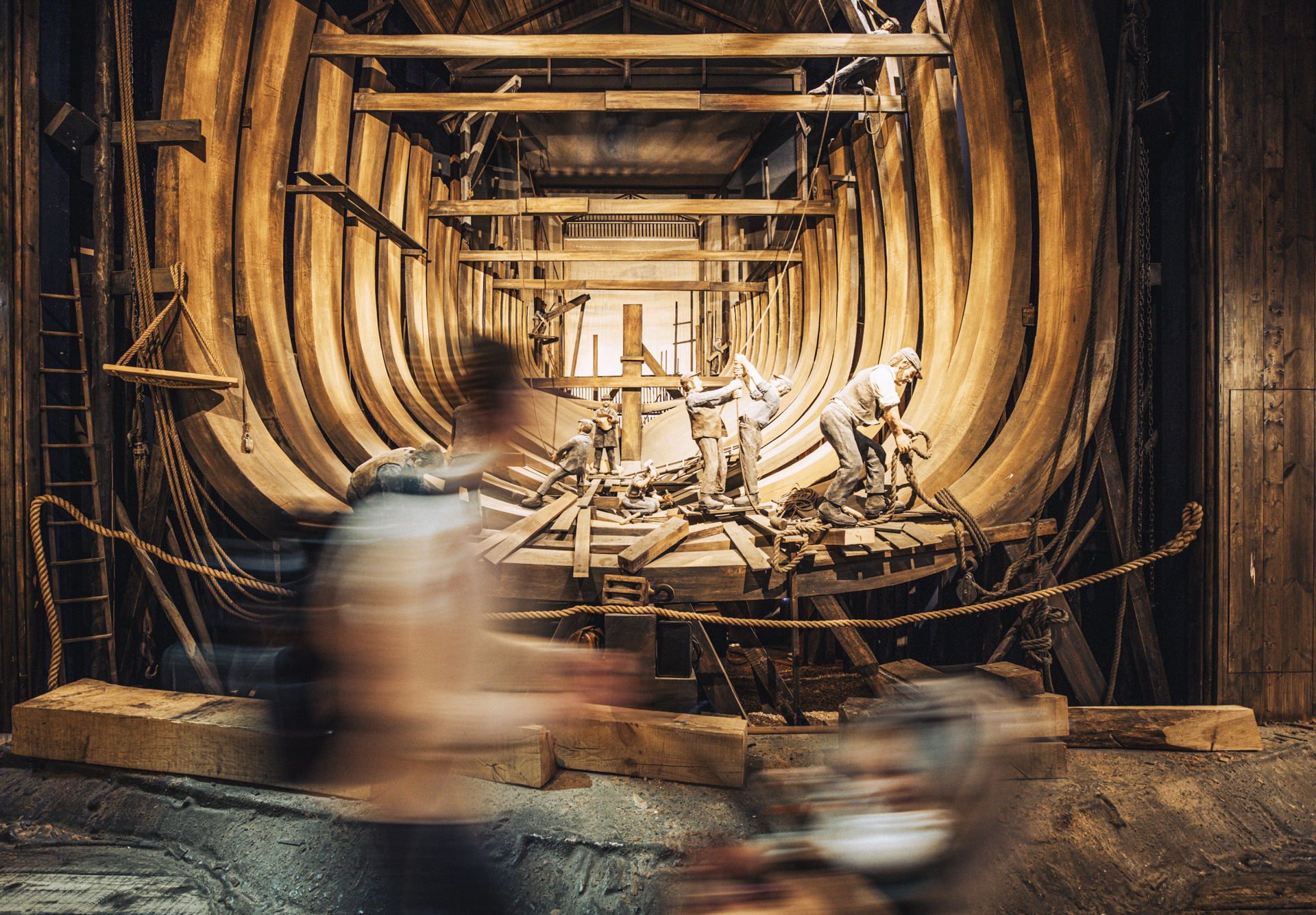 A visitor walks by a diorama of the inside of the RRS Discovery during its construction in the Dundee dockyards. A golden glow radiates from behind the ship's structure.